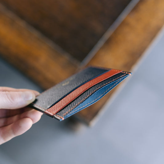 Hand holding a leather wallet with a wooden surface in the background