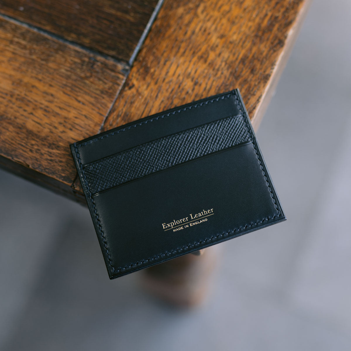 Black leather cardholder on a wooden surface
