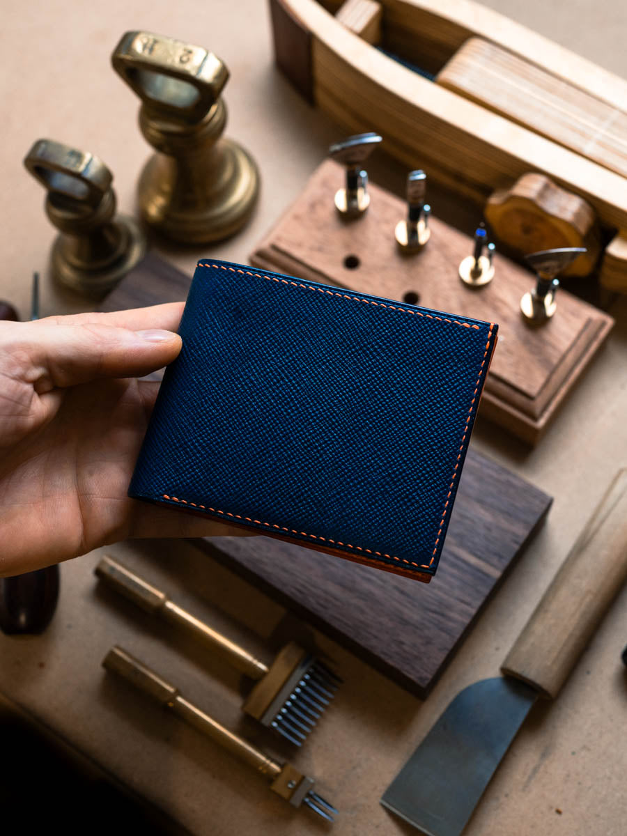 Closed navy leather bifold wallet on a workbench