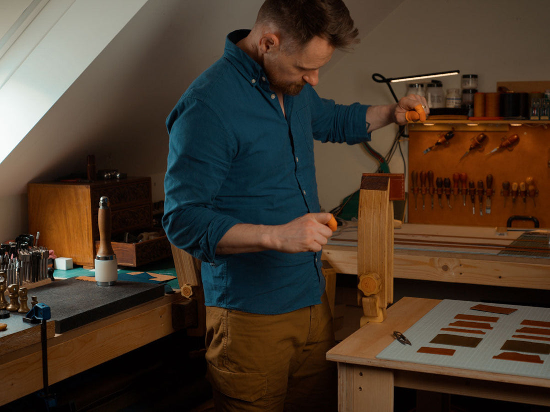 Nick saddle stitching a leather wallet panel in the Explorer Leather workshop