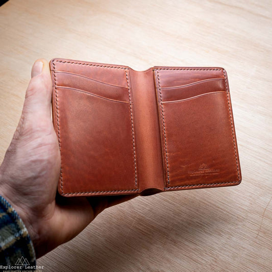 Shell Cordovan Brown leather wallet held by a hand on a wooden surface