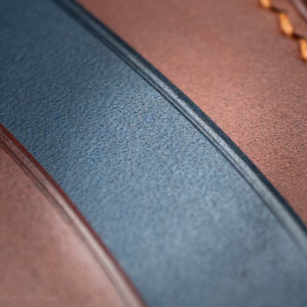 close up detail images of leather wallet pocket to show burnishing and creasing, navy blue and tan brown leather