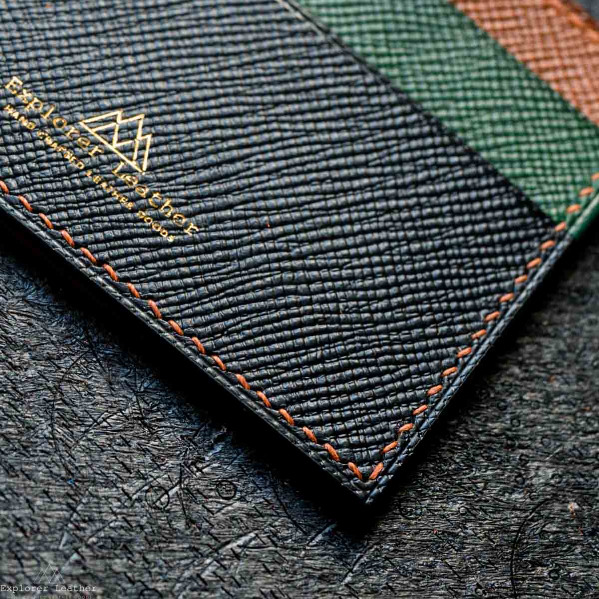 Close-up of a textured leather with embroidered branding on a dark surface.