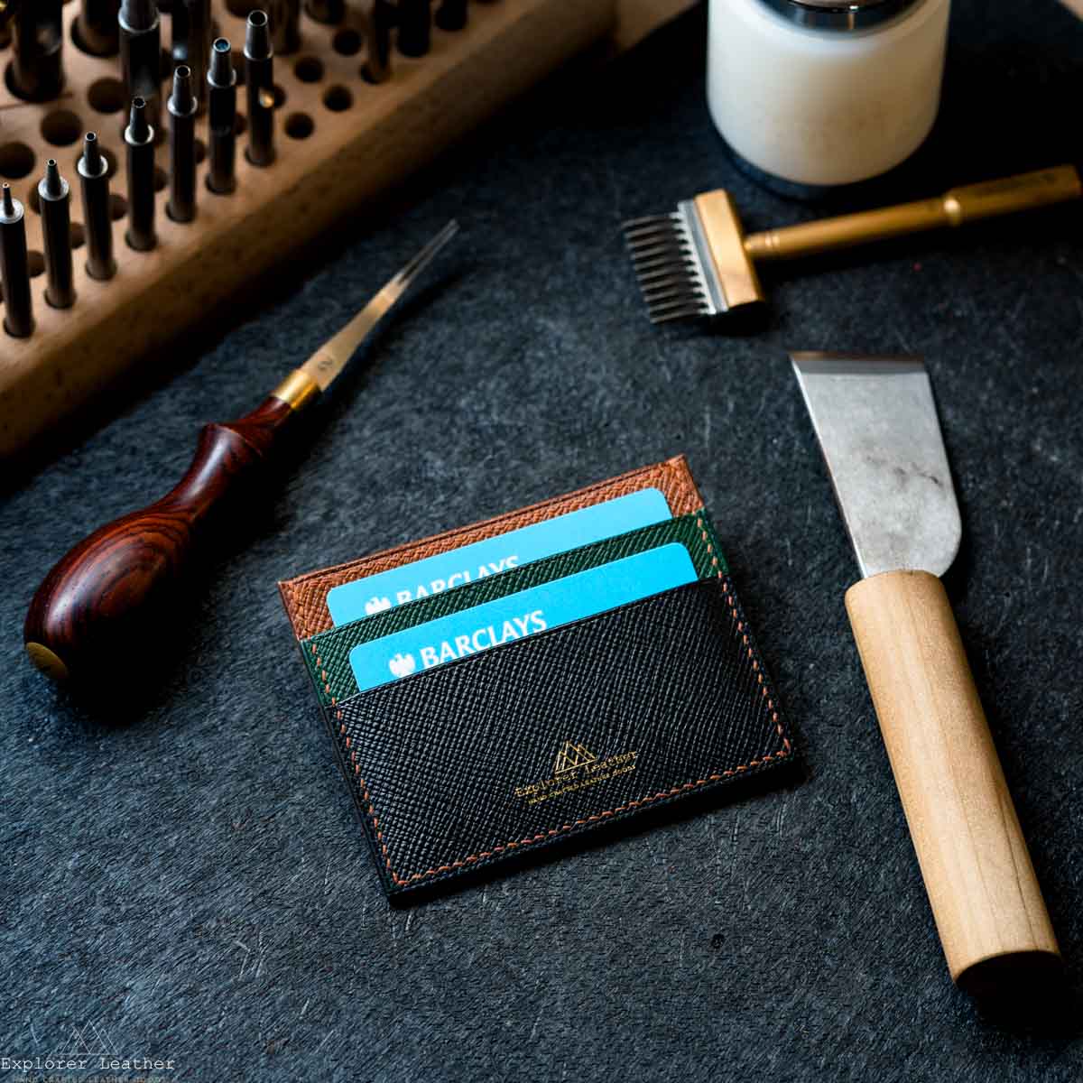 Black,Green and brown leather wallet with cards on a dark surface with tools
