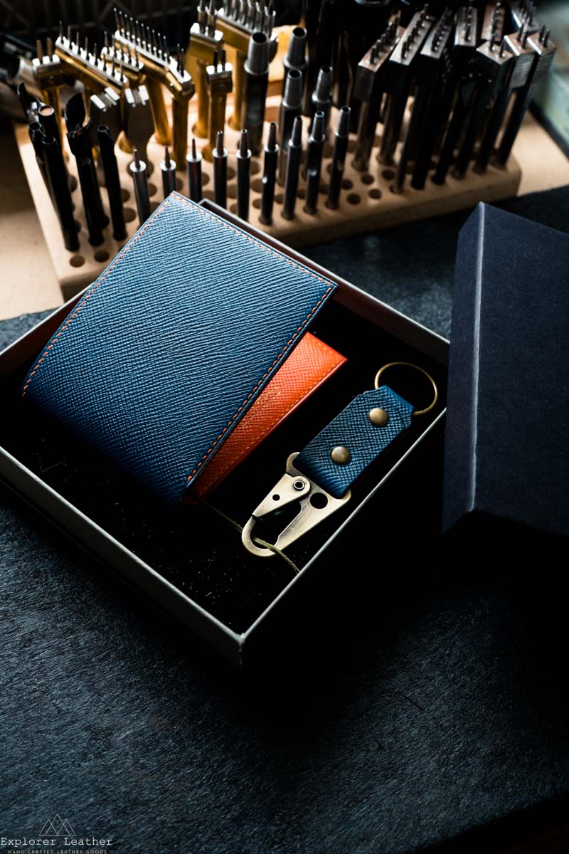 Blue leather wallet and keychain set with tools in the background