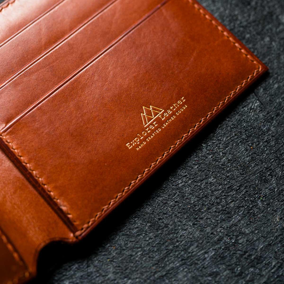 Brown leather wallet with Explorer leather branding on a dark textured surface