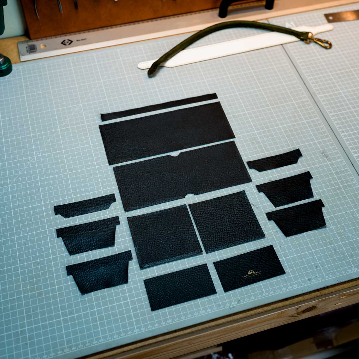 Black leather pieces arranged on a cutting mat with a ruler in the background
