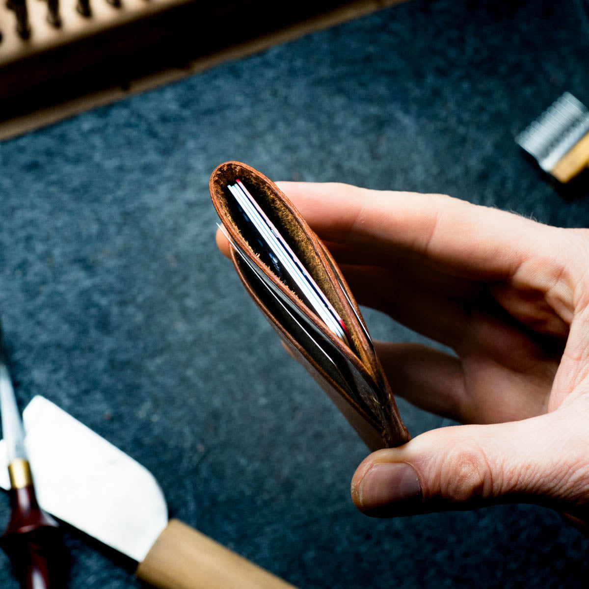 Hand holding a wallet against a textured dark background