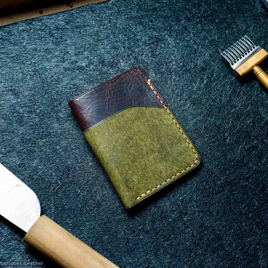 Green leather wallet on a dark textured surface with a tool and knife.