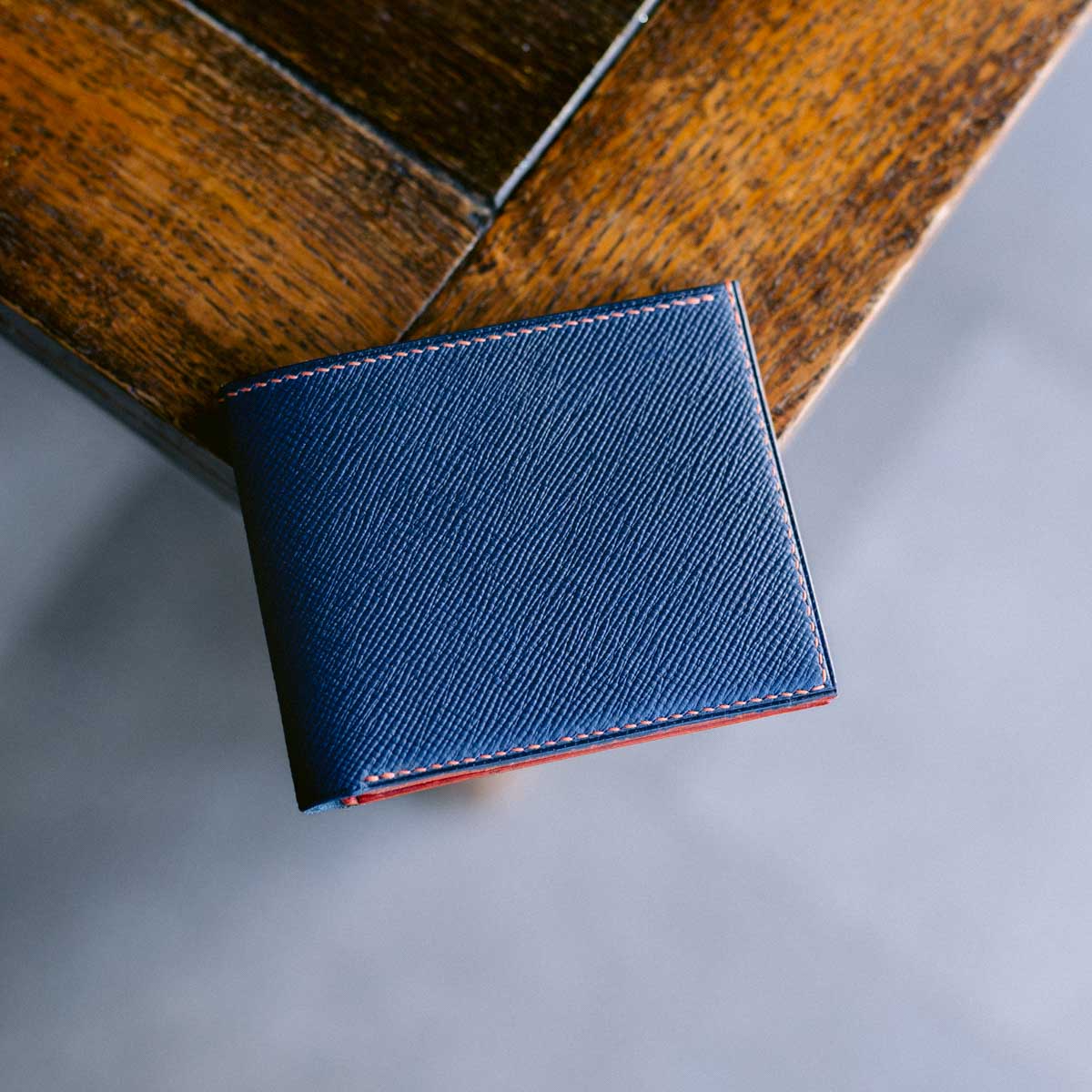 Blue and orange leather wallet on a wooden surface