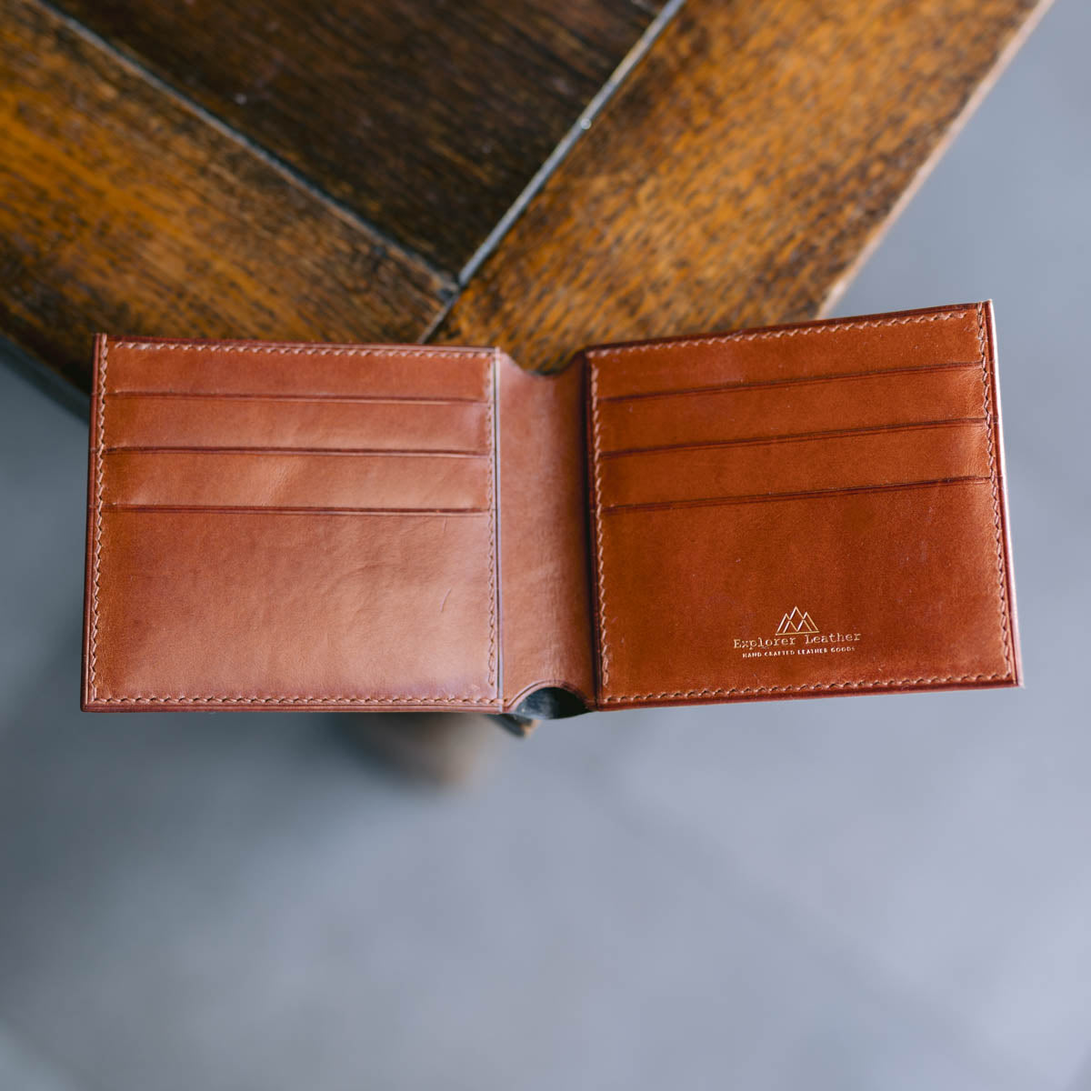 black and Brown leather wallet with visible brand logo on a gray surface.