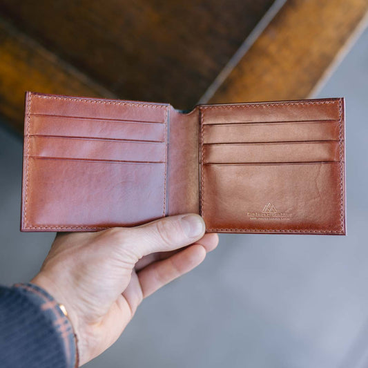Brown leather wallet held by a hand with a blurred background
