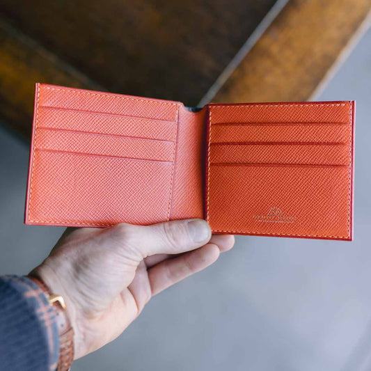 Blue and orange leather wallet held open by a hand with a blurred background