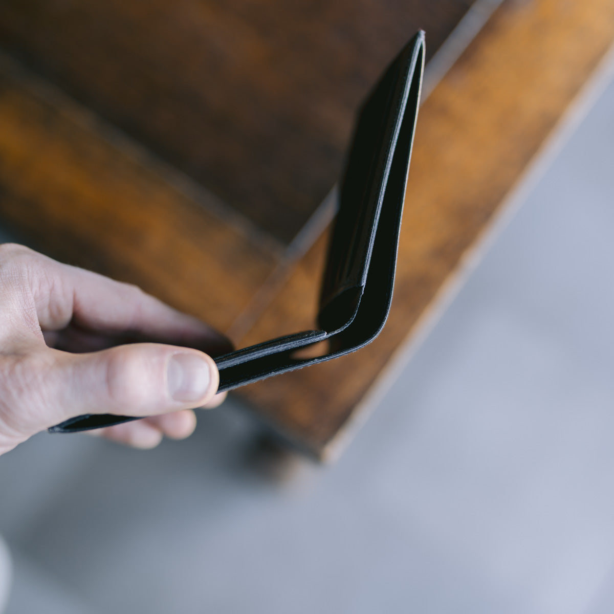 Hand holding a black wallet against a blurred background