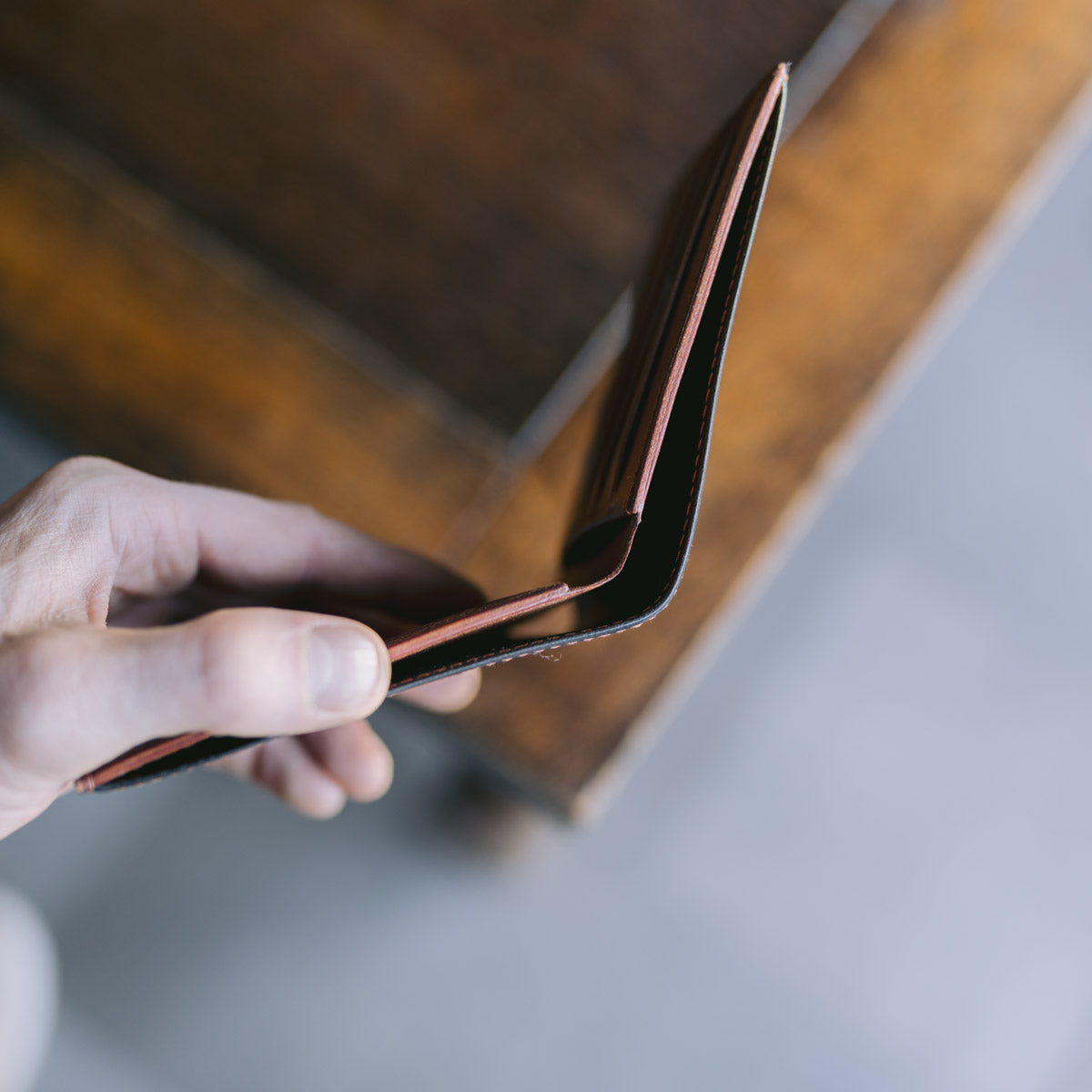 Hand holding a black and brown leather wallet against a blurred background