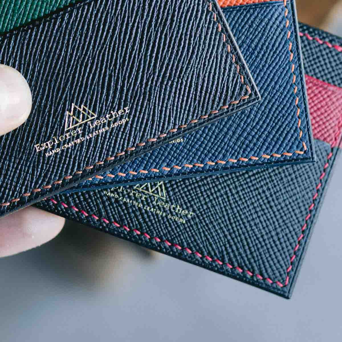 Close-up of a leather card holders with visible explorer leather branding on a neutral background