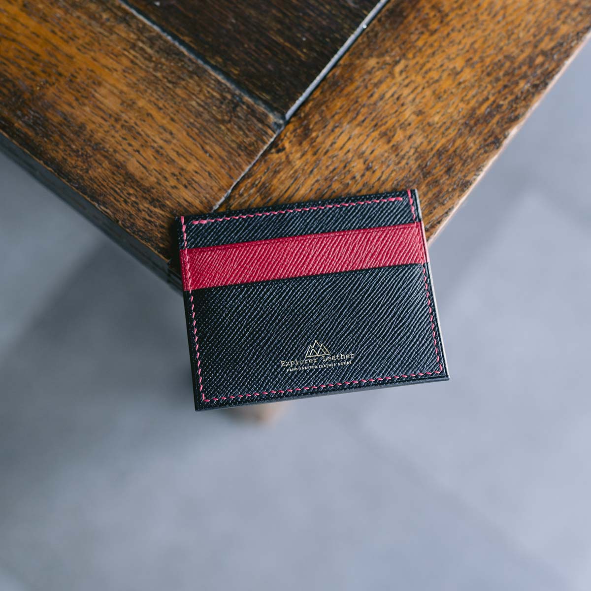 Black and red leather cardholder on a wooden surface