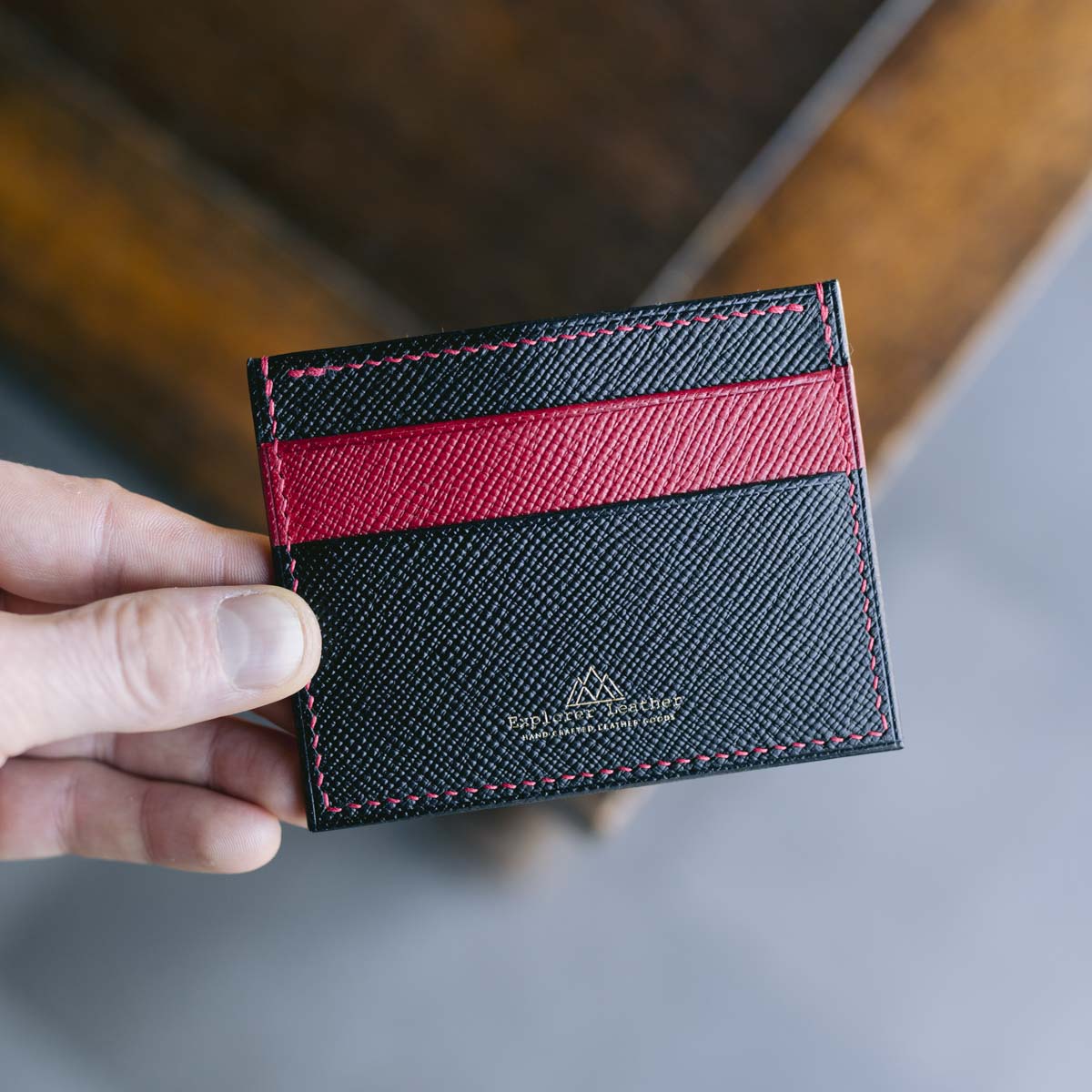 Black and red cardholder held by a hand on a blurred background