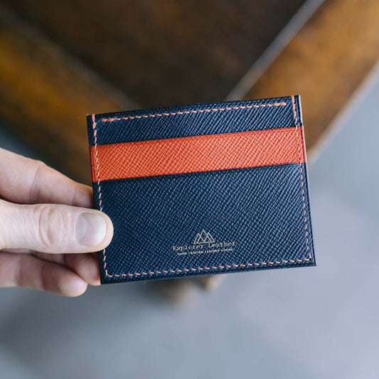 Navy blue and orange cardholder  held by a hand on a blurred background