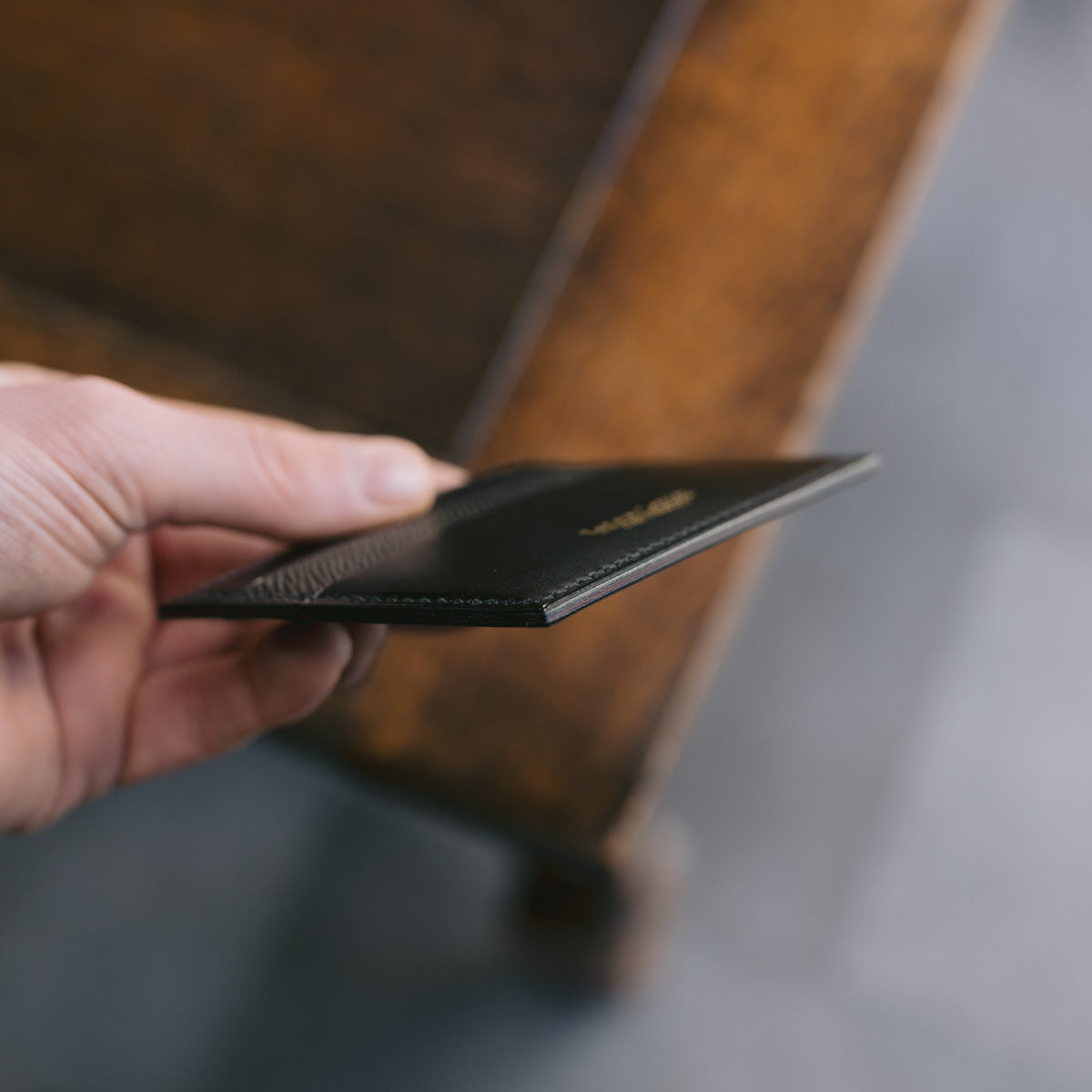 Hand holding a black leather wallet with a blurred background