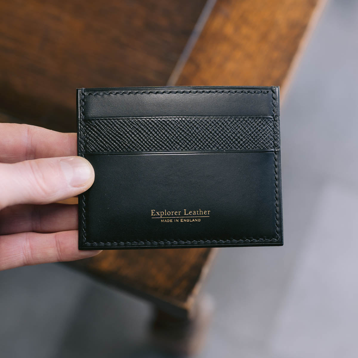 Black leather cardholder with 'Explorer Leather' branding held by a hand.