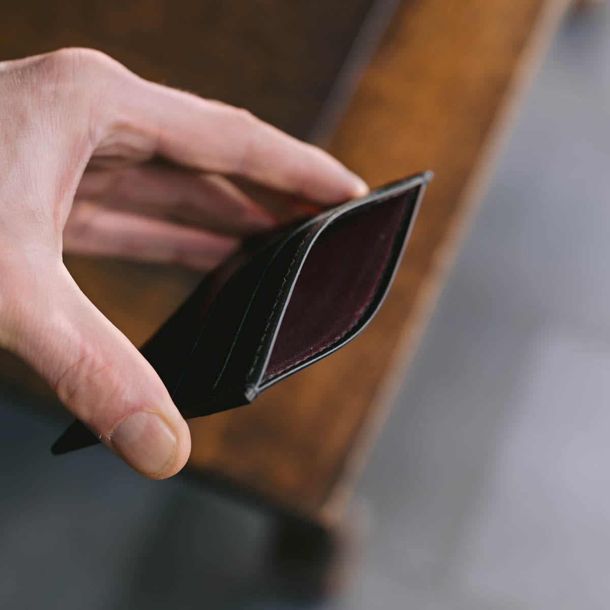 Hand holding a black leather wallet against a blurred background