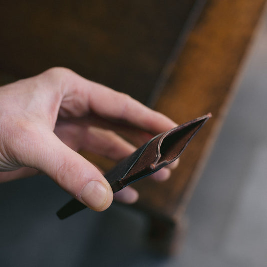 Hand holding a leather wallet with a blurred background showing the centre part open