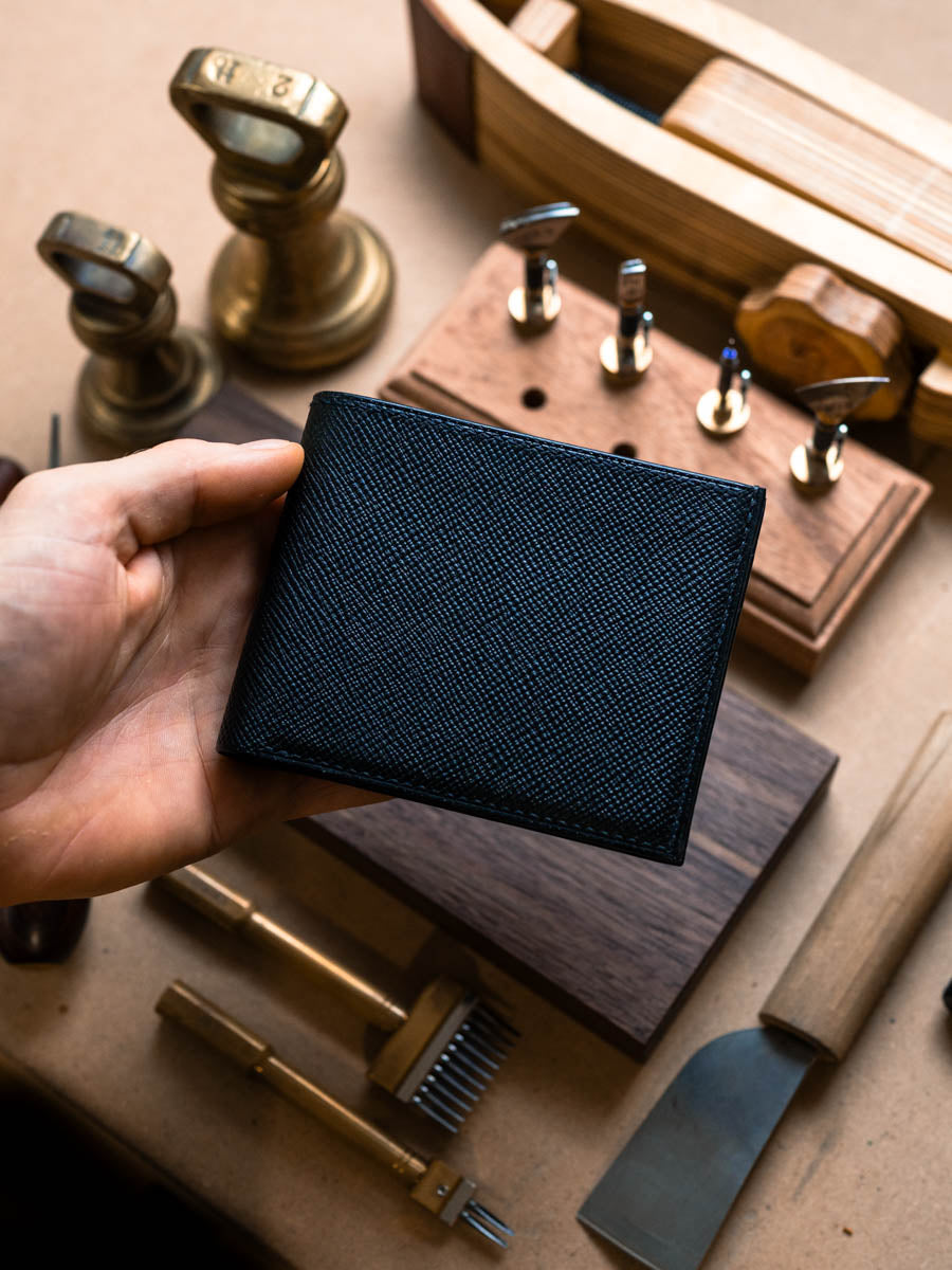Closed black leather bifold wallet held in hand