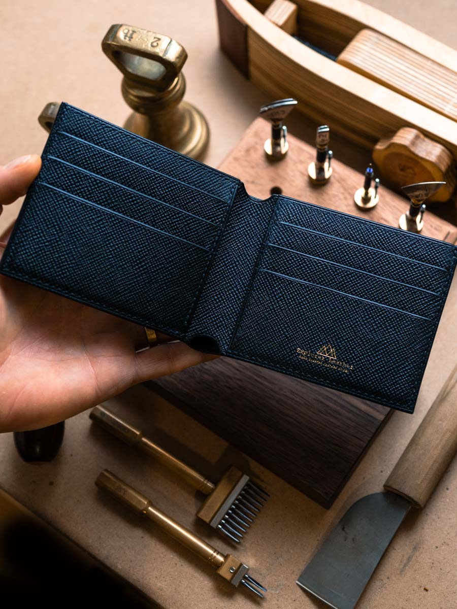 Open black leather bifold wallet held in hand