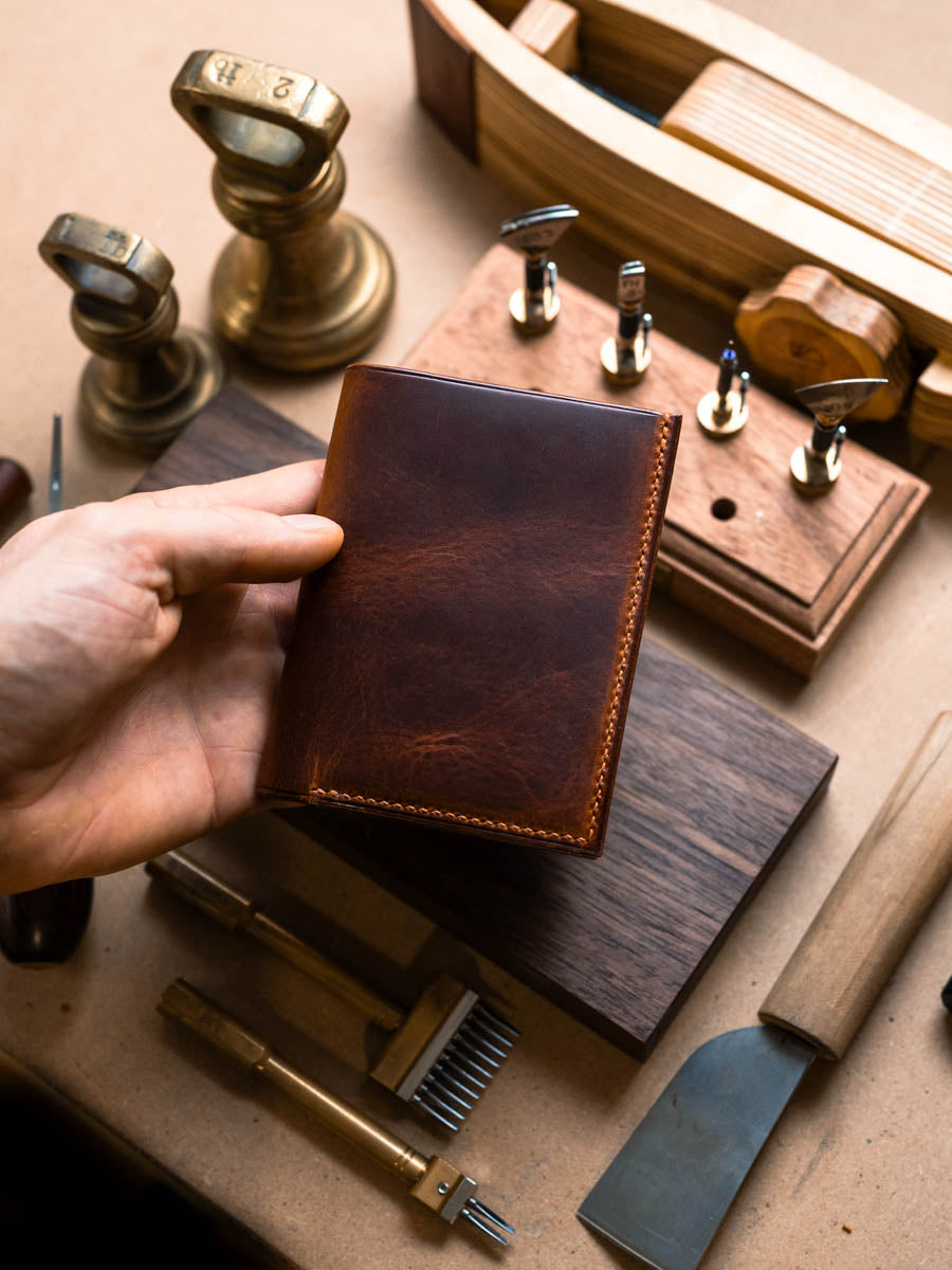Closed Cognac and navy vertical bifold wallet held in hand