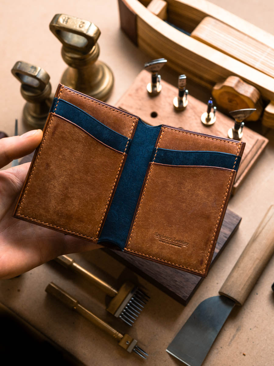 Open Cognac and navy vertical bifold wallet showing navy panels
