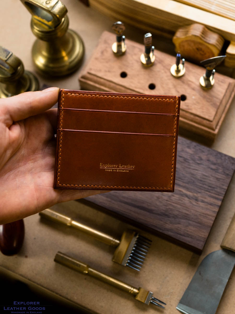Cognac five pocket leather card holder held in hand, showing card pockets and tan stitching