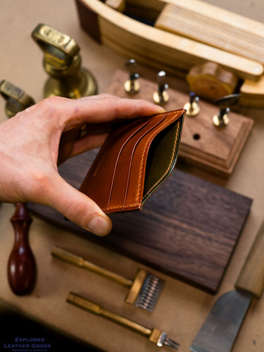 Cognac leather card holder opened to show its olive green inner and central pocket