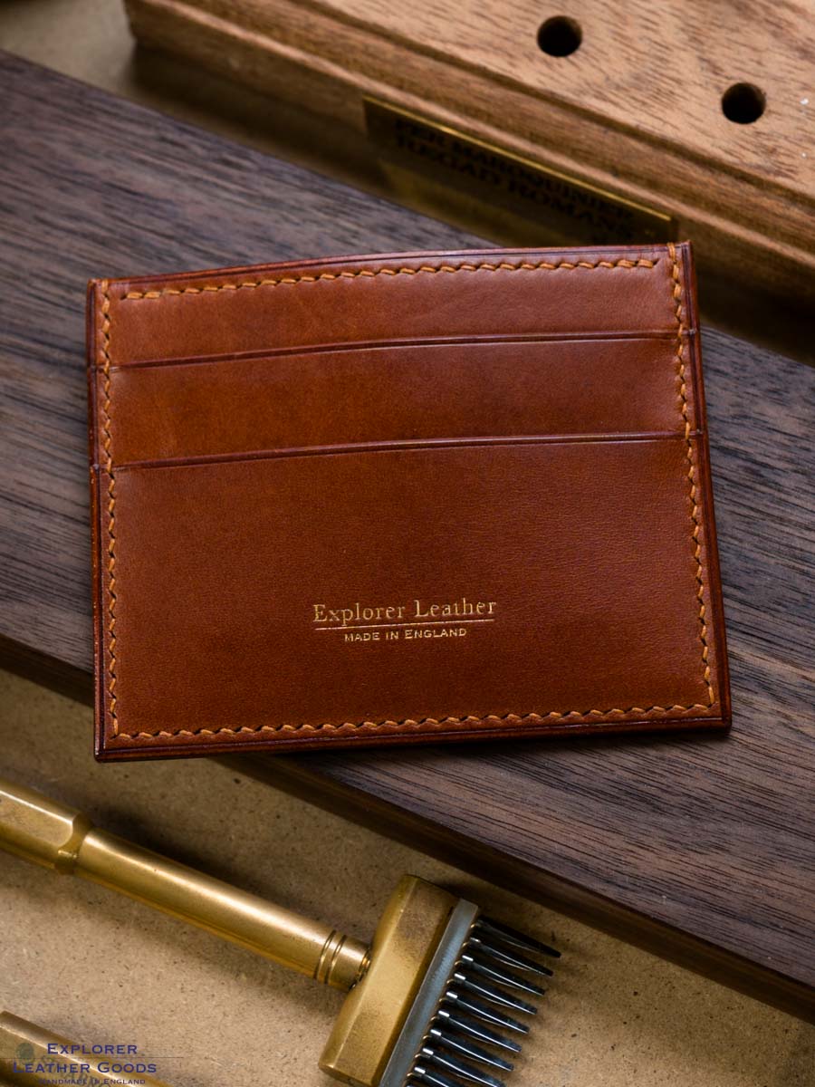 Close-up of the gold Explorer Leather maker’s mark and tan stitching on cognac leather